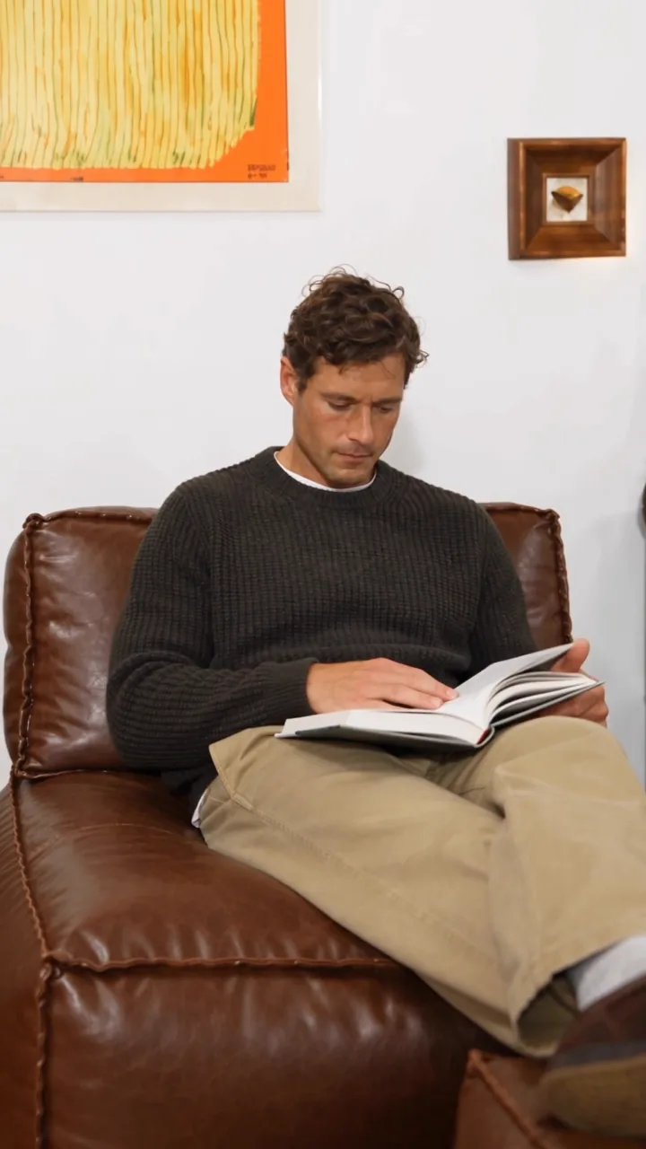 Reading in a brown lounge chair in a living room